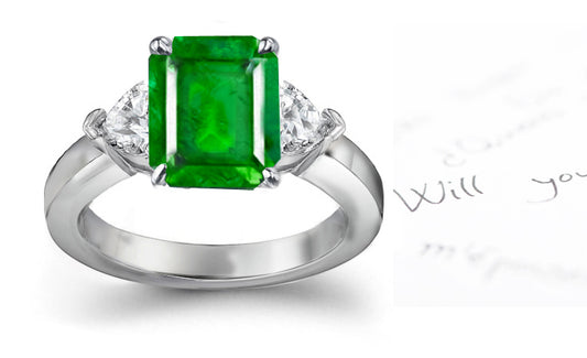 engagement ring three stone with emerald cut emerald center and side heart diamonds