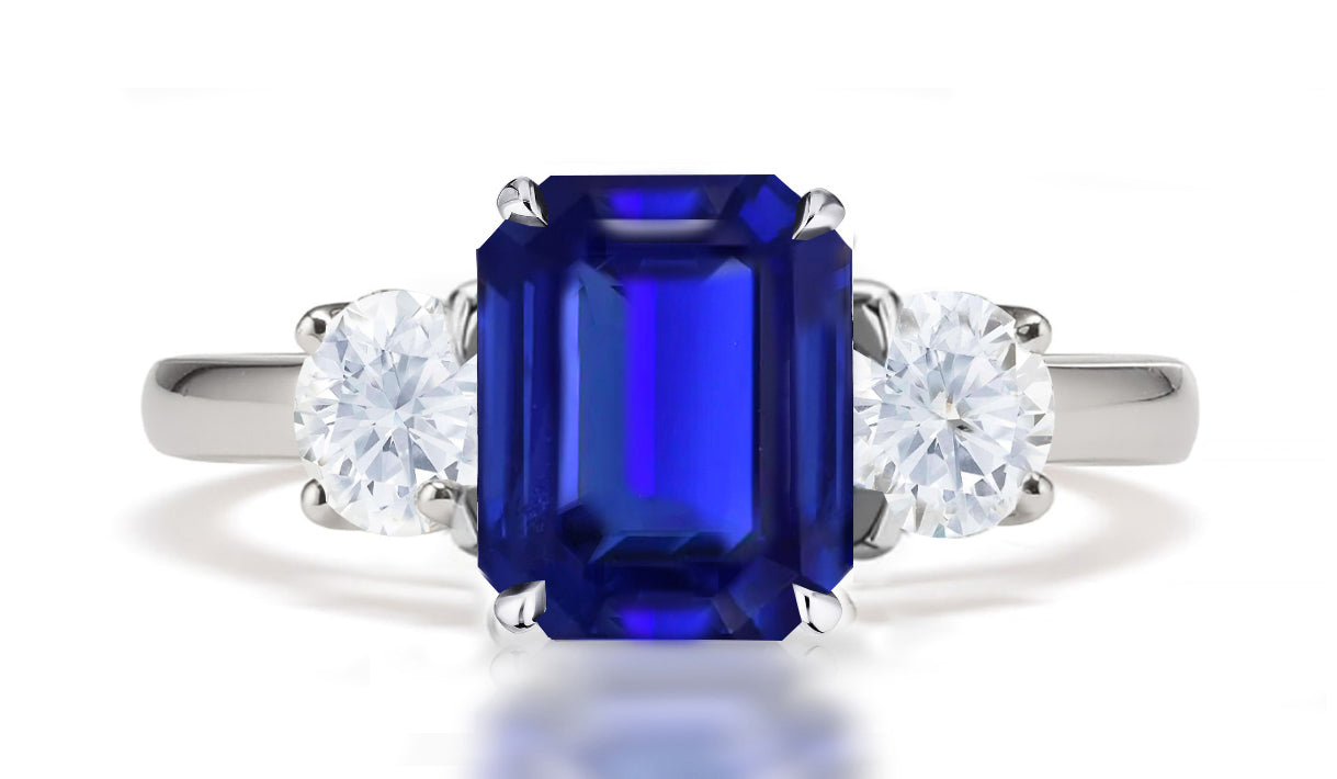 290 custom made unique emerald cut blue sapphire center stone and round diamond accent three stone engagement ring.