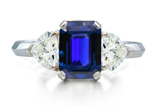 517 custom made unique emerald cut blue sapphire center stone and heart diamond accent three stone engagement ring