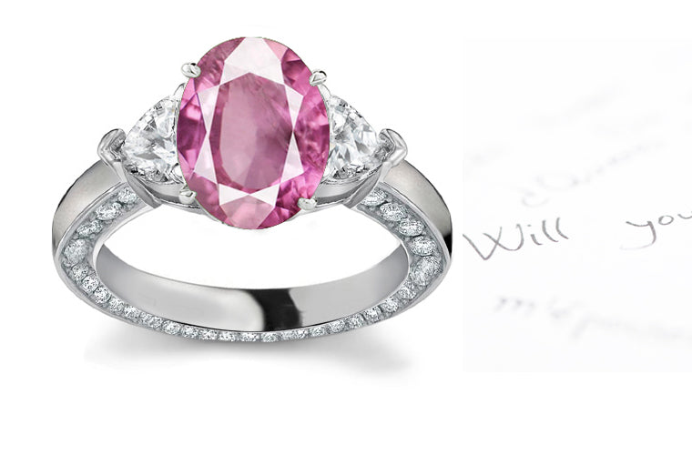 engagement ring handcrafted with oval pink sapphire center and side heart diamonds