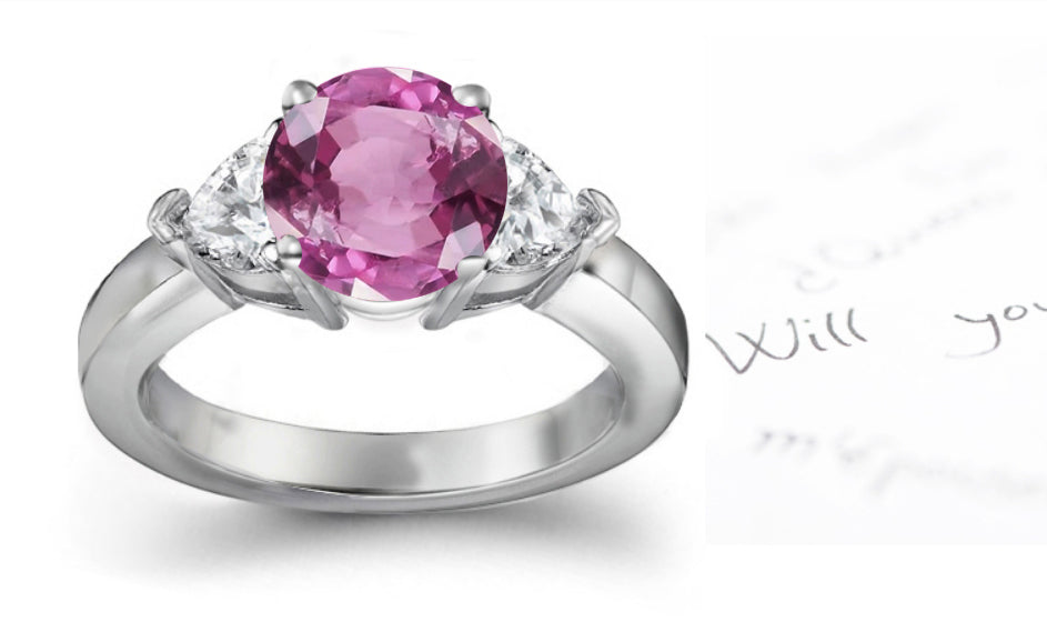 engagement ring with round pink sapphire center and side heart diamonds